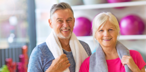 A man and woman are smiling in front of exercise equipment